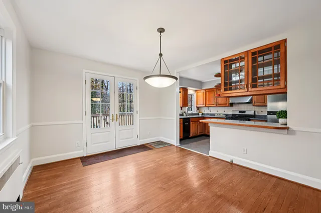 a dining room with wooden floor a chandelier a wooden table and chairs