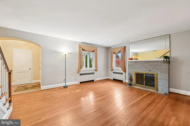 an empty room with wooden floor fireplace and windows
