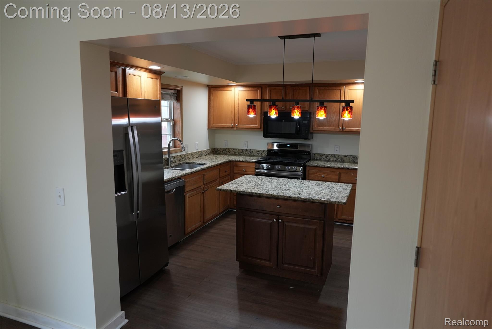 2018 John R Road Troy, MI 48083 - Photo 12 of 57 Kitchen featuring stainless steel appliances, wood-finish flooring, granite countertops, wood cabinetry, and an island with storage