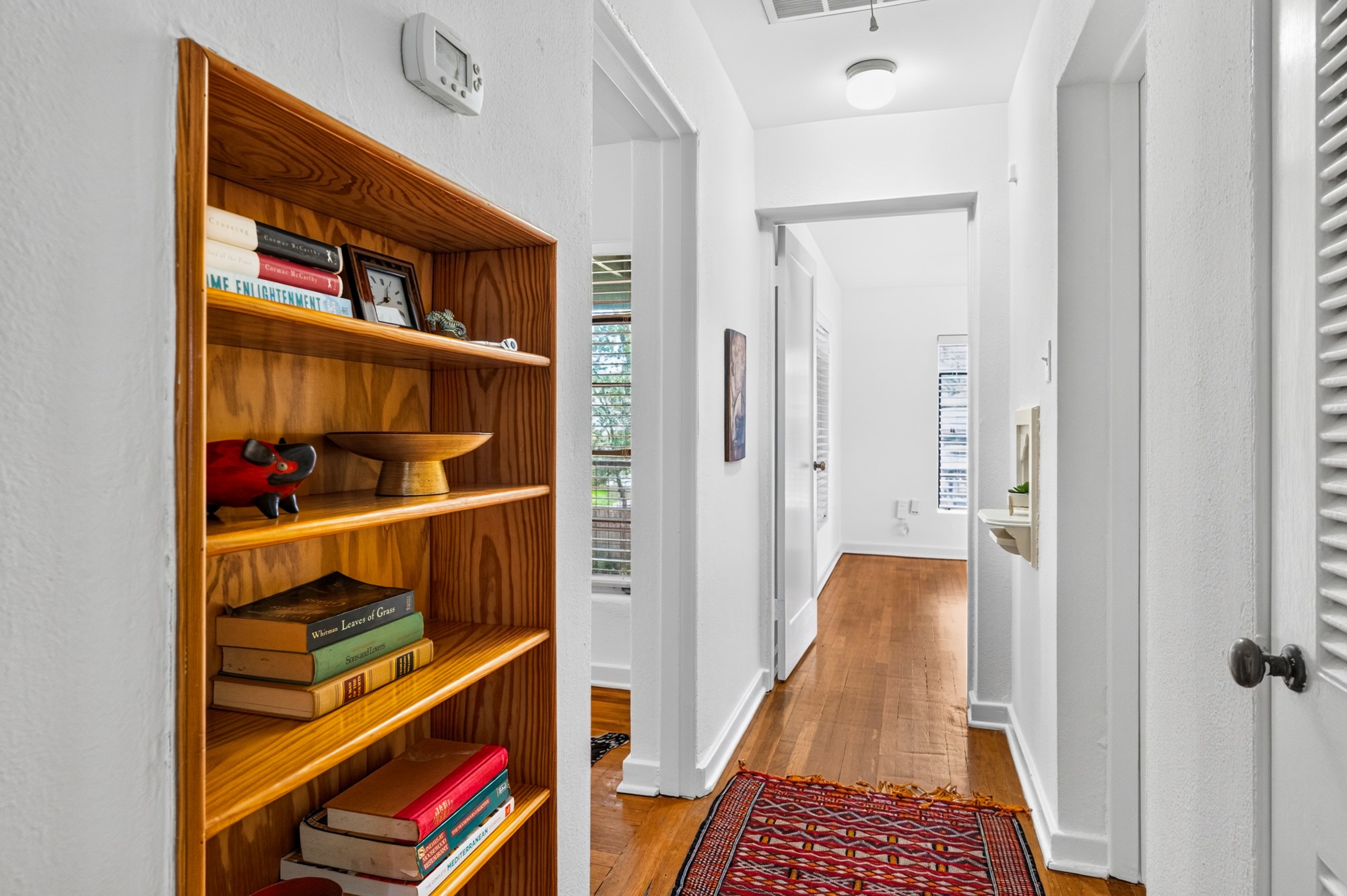 1302 Kirkwood Road, Unit B Austin, TX 78722 - Photo 15 of 21 A well-lit hallway showcasing polished hardwood flooring and convenient built-in shelving.