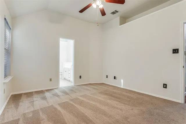 an empty room with chandelier fan and windows