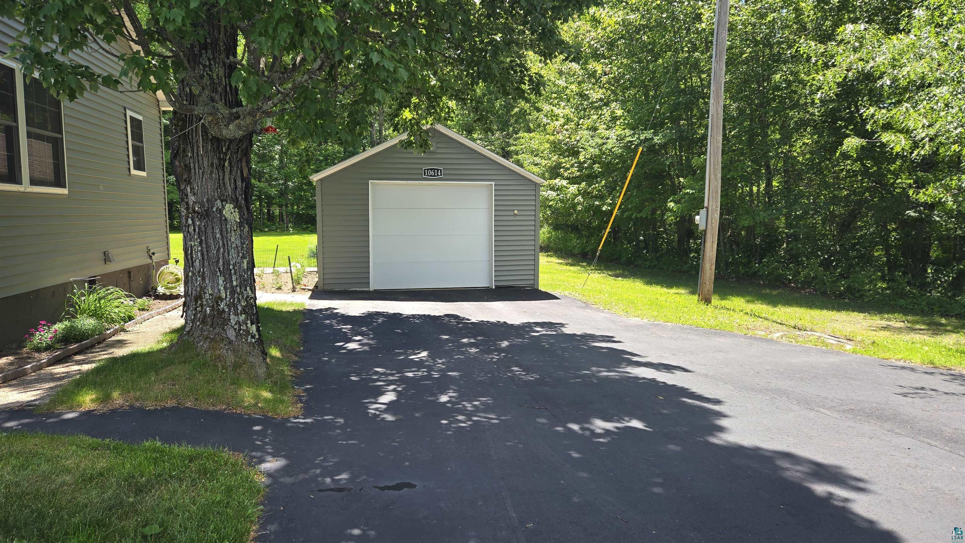 10614 Moose Lake Road Orr, MN 55771 - Photo 41 of 44 Detached garage with a white overhead door and horizontal siding, situated on an asphalt driveway