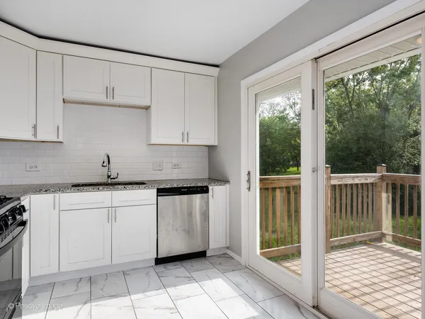 a kitchen with granite countertop a sink window and cabinets