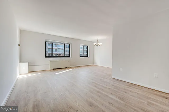 a view of a big room with wooden floor and windows