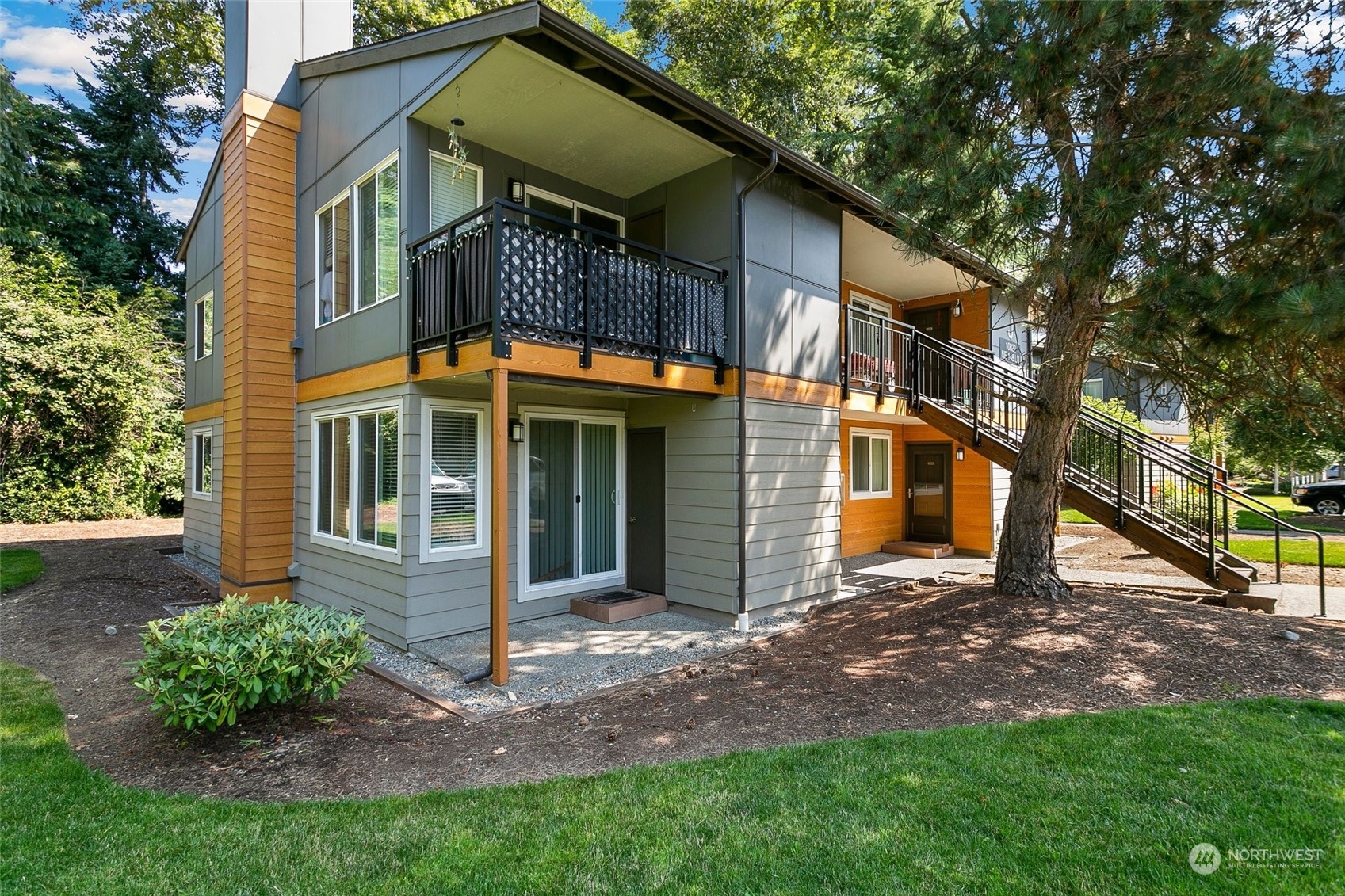 10822 Northeast 148th Lane, Unit J101 Bothell, WA 98011 - Photo 2 of 22 a view of a brick house with many windows plants and large tree