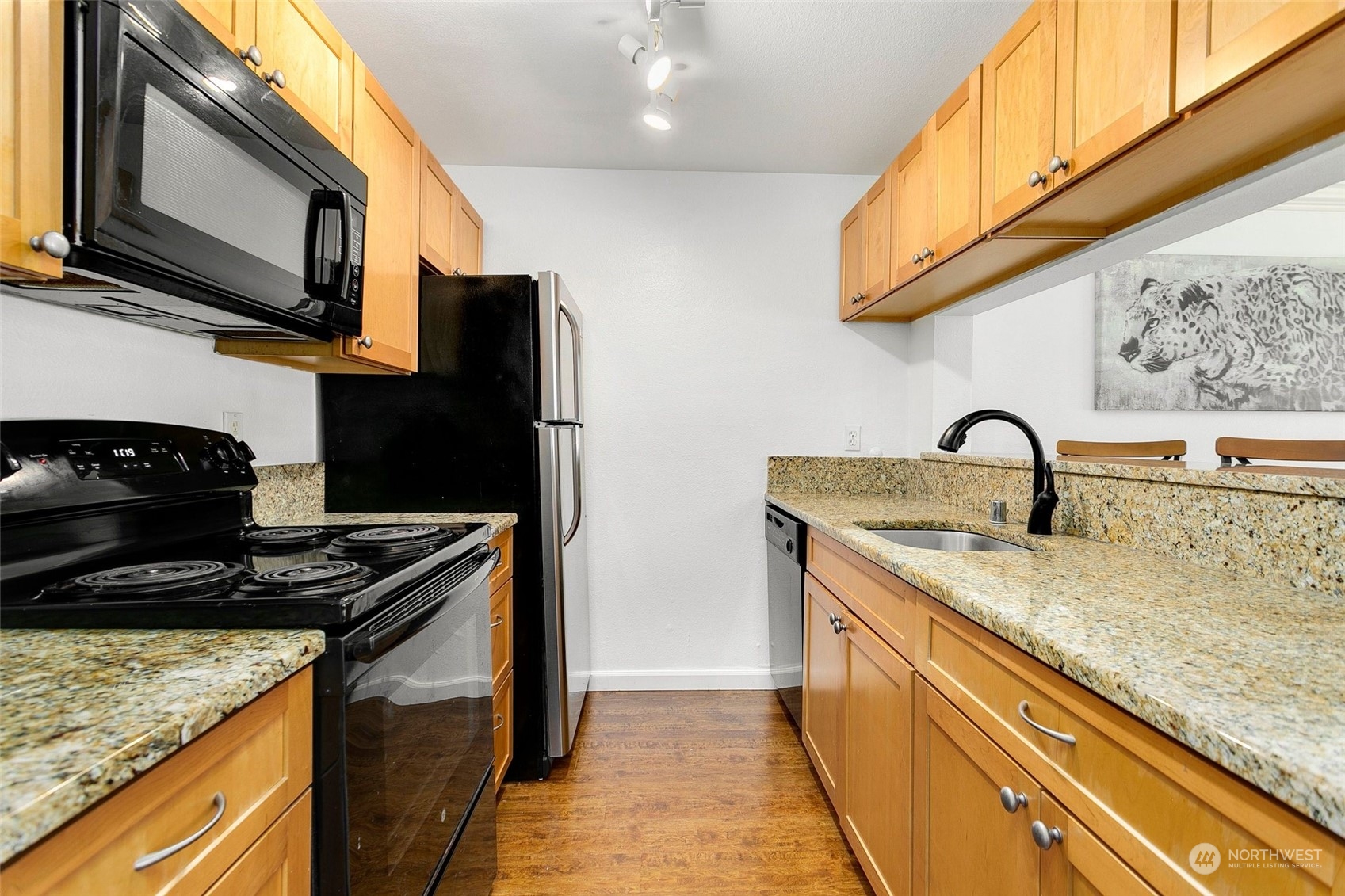 10822 Northeast 148th Lane, Unit J101 Bothell, WA 98011 - Photo 8 of 22 a kitchen with stainless steel appliances granite countertop a sink a stove and a microwave