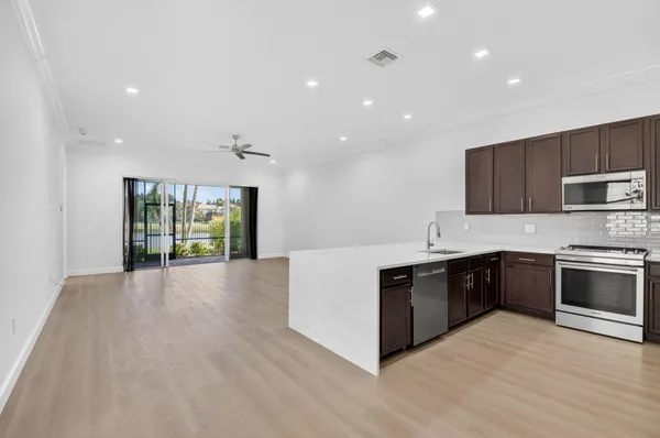 a view of a kitchen with cabinets stainless steel appliances wooden floor and a window
