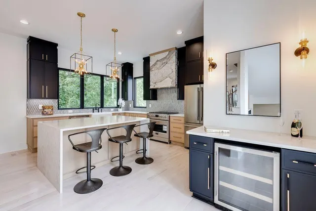 a large kitchen with stainless steel appliances a large counter top a stove a chimney a sink and a refrigerator