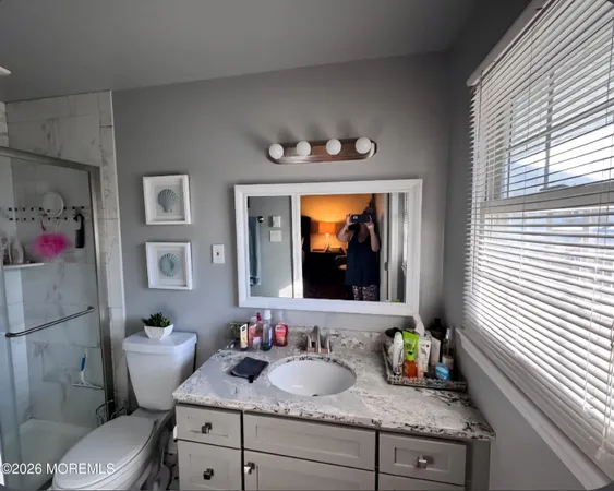 a bathroom with a granite countertop sink a mirror and a toilet