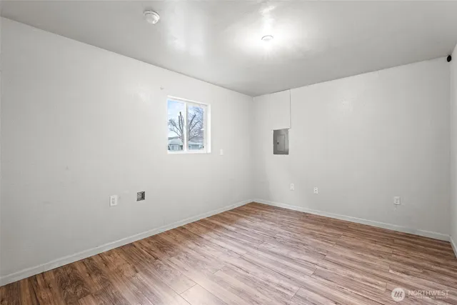 an empty room with wooden floor and windows