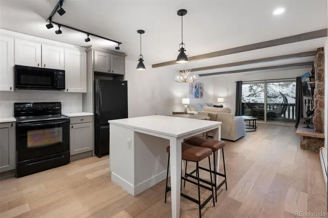 a kitchen with a sink stainless steel appliances and wooden floor