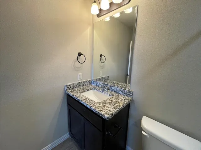 a bathroom with a granite countertop sink and a toilet
