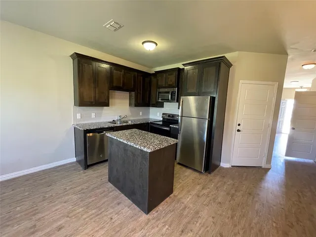 a kitchen with stainless steel appliances granite countertop a refrigerator and a stove