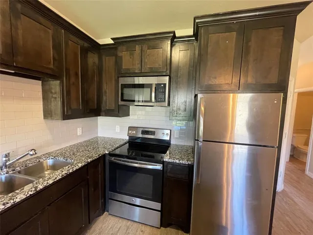 a kitchen with granite countertop a refrigerator stove and microwave