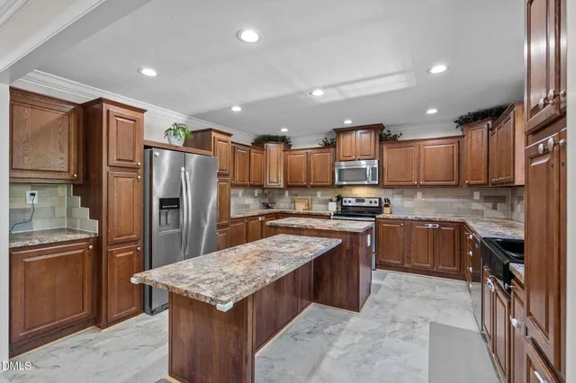 a large kitchen with stainless steel appliances granite countertop a stove top oven a refrigerator a sink and dishwasher wooden cabinets with wooden floor