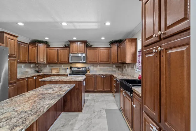 a kitchen with granite countertop kitchen island stainless steel appliances a sink stove and table