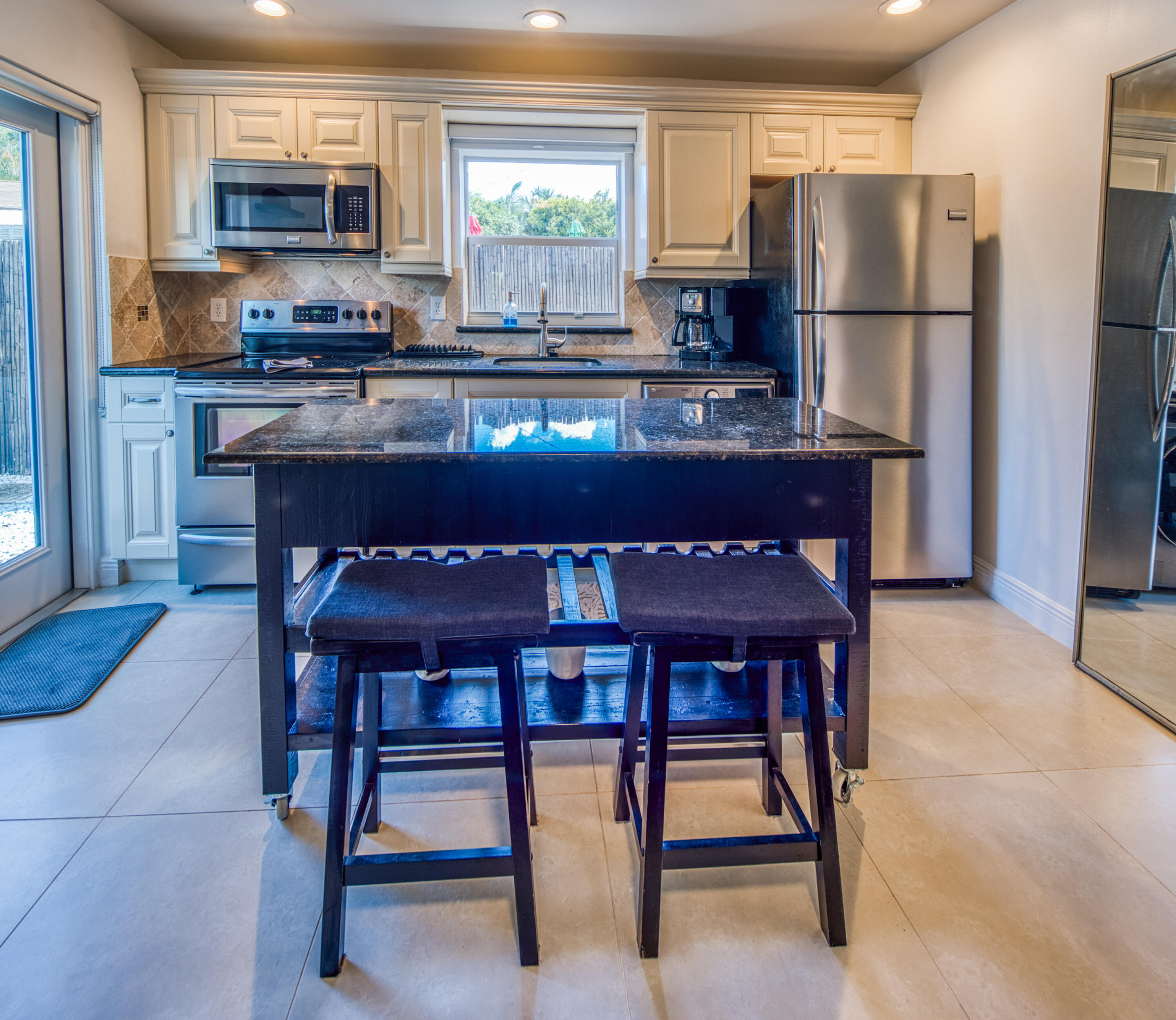 1331 North N Street, Unit GUEST HOUSE Lake Worth Beach, FL 33460 - Photo 2 of 23 a kitchen with stainless steel appliances granite countertop a dining table chairs refrigerator and sink