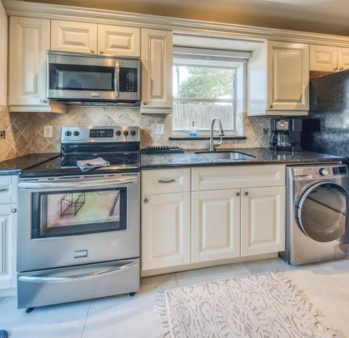 a kitchen with granite countertop white cabinets and stainless steel appliances