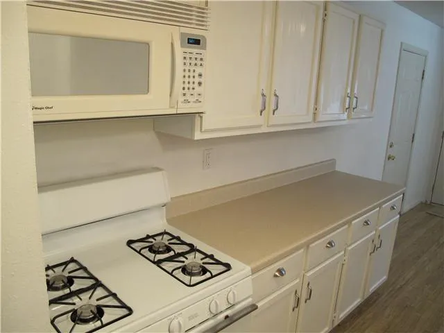 a kitchen with white cabinets and appliances
