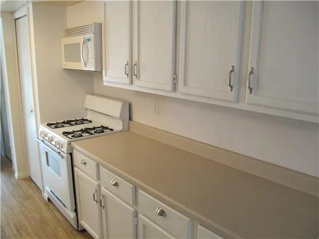 a kitchen with white cabinets and appliances