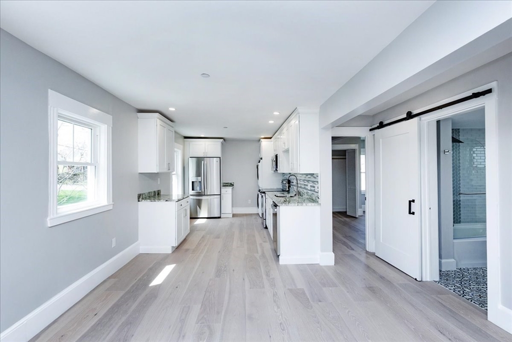 22 Berkley Road, Unit 2 Hull, MA 02045 - Photo 19 of 39 a large white kitchen with white cabinets and wooden floor