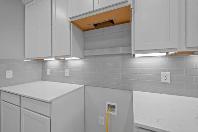 a large white kitchen with kitchen island a sink stainless steel appliances and cabinets