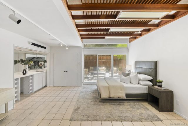 a bed sitting in a bedroom next to a window with a potted plant