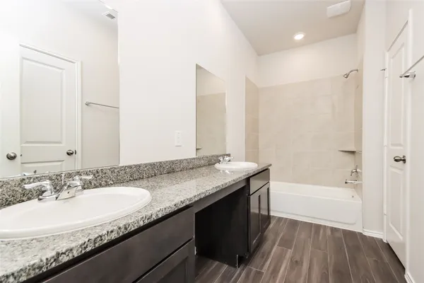 a bathroom with a granite countertop sink a mirror a bathtub and shower