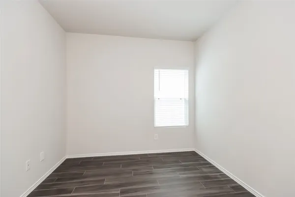an empty room with wooden floor and window