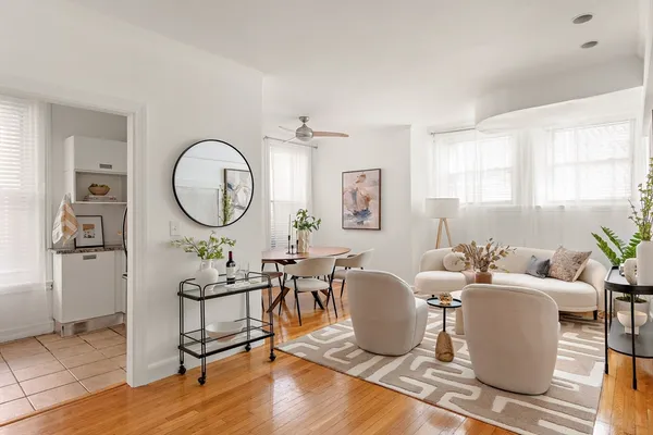 a living room with couches a mirror and a dining table with wooden floor