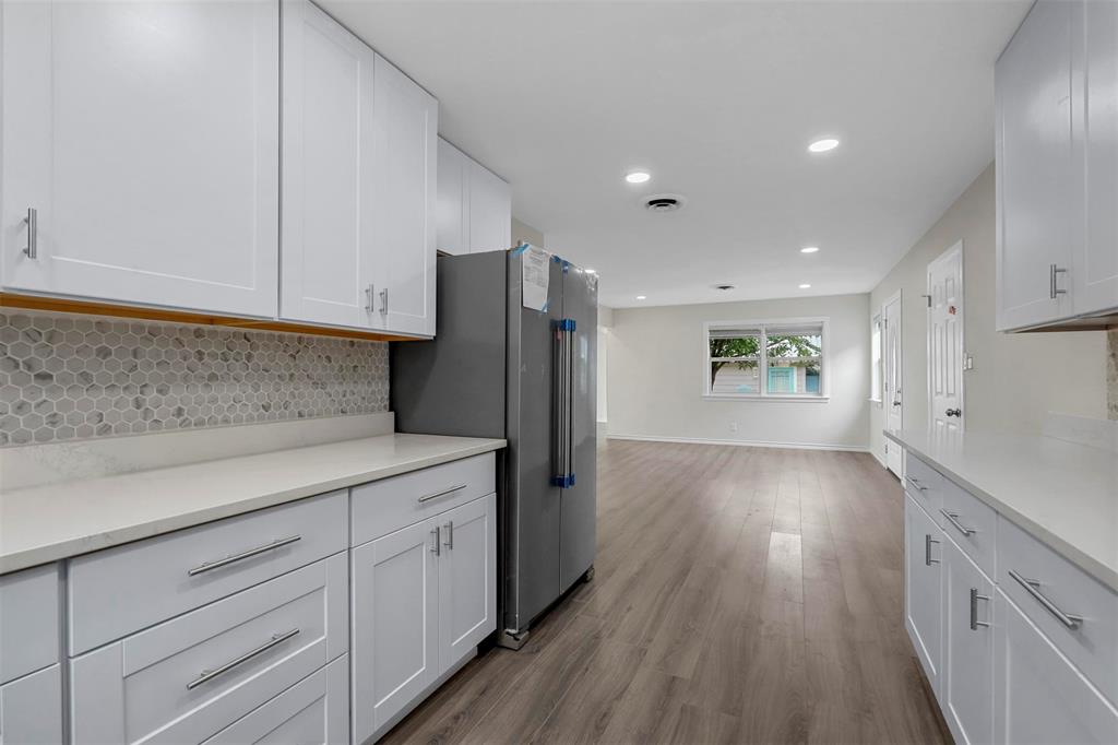 8048 Woodvale Road Fort Worth, TX 76135 - Photo 27 of 27 Kitchen featuring white cabinets, light hardwood / wood-style flooring, stainless steel refrigerator, and decorative backsplash