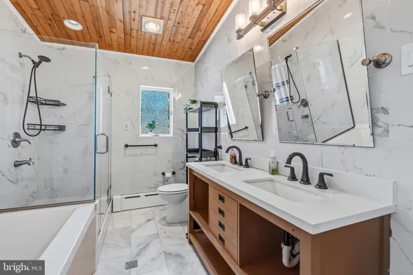a bathroom with a double vanity sink toilet mirror and bathtub