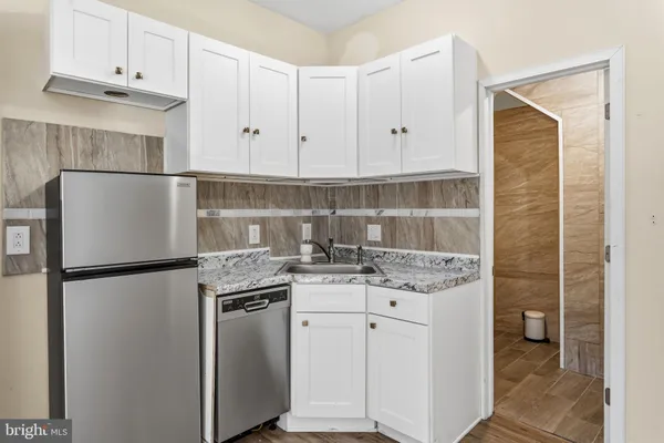 a kitchen with stainless steel appliances granite countertop a refrigerator a stove a sink and white cabinets