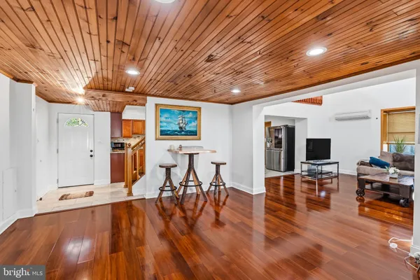 a livingroom with furniture wooden floor a flat screen tv and a chandelier