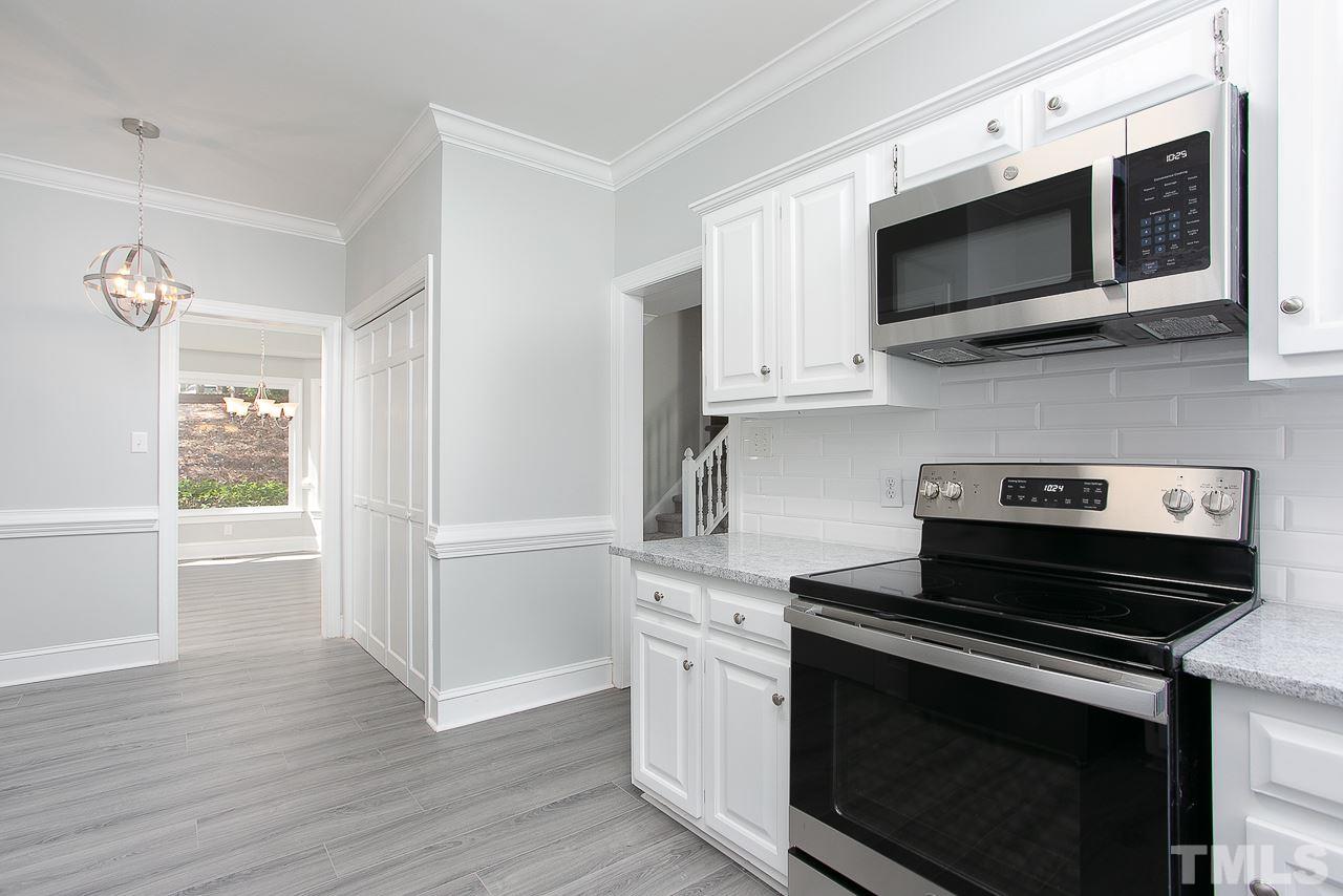 6830 Gloucester Road Raleigh, NC 27612 - Photo 5 of 28 a kitchen with stainless steel appliances a stove a microwave oven cabinets and a wooden floor