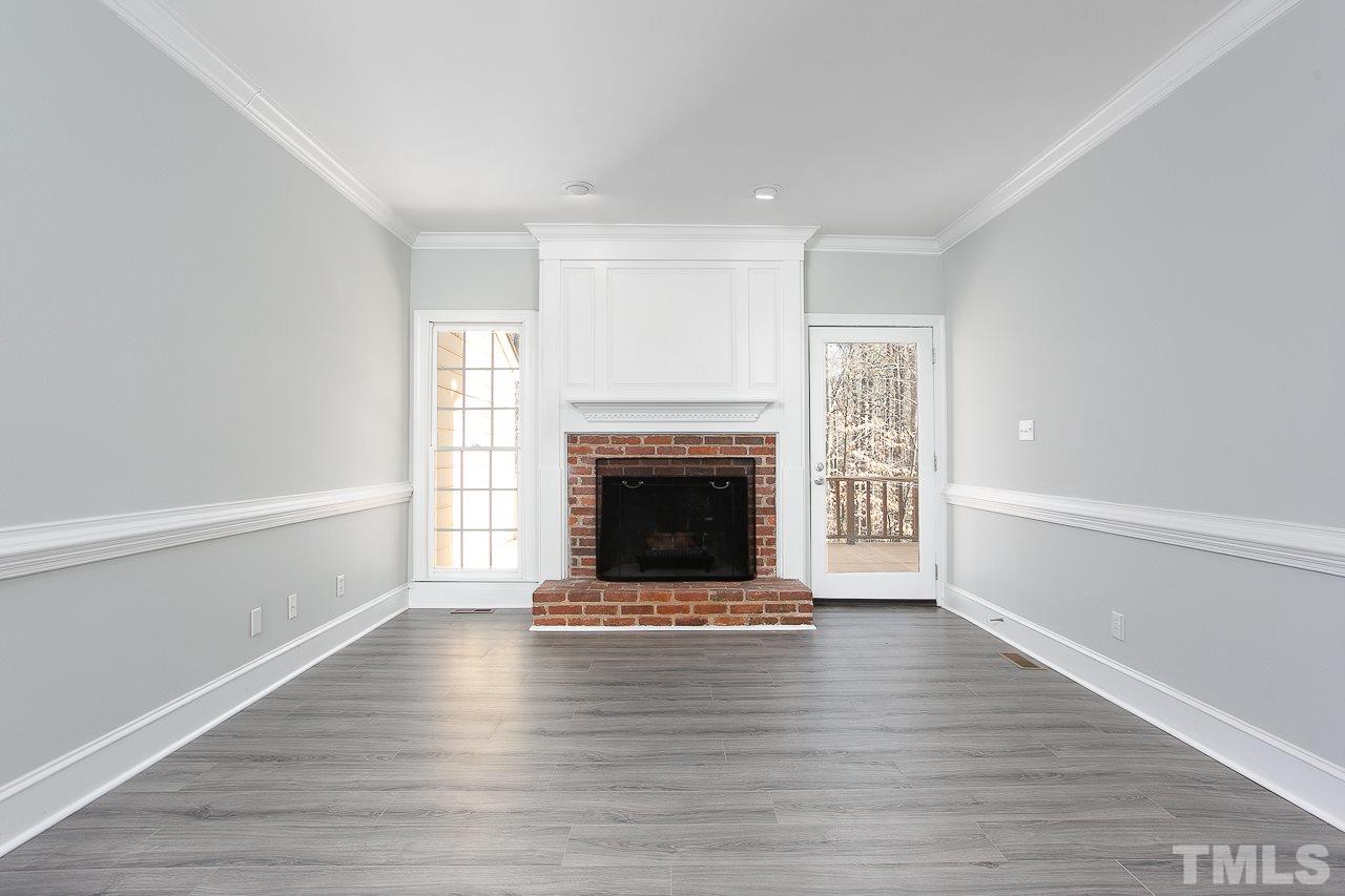 6830 Gloucester Road Raleigh, NC 27612 - Photo 8 of 28 a view of an empty room with wooden floor fireplace and a window