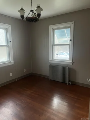 an empty room with wooden floor chandelier fan and windows