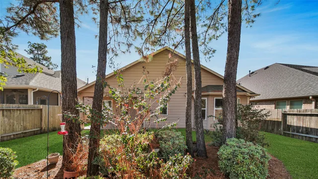 a view of a backyard with table and chairs potted plants and large tree