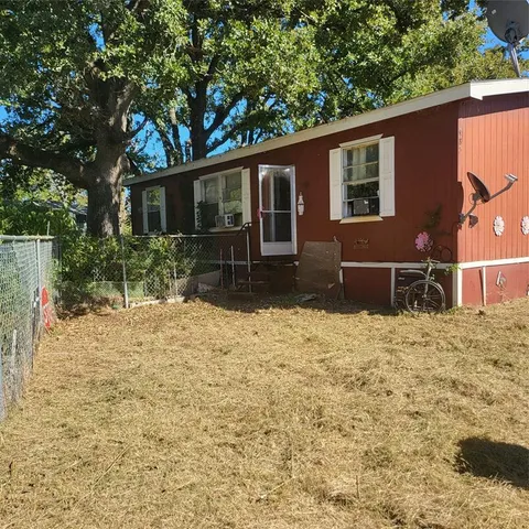 a backyard of a house with a large tree and wooden fence