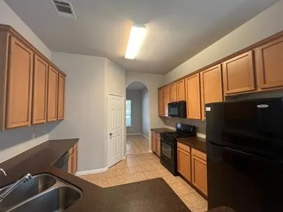 a kitchen with granite countertop a refrigerator stove and sink