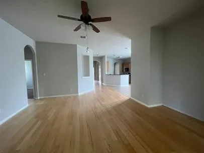 a view of empty room with wooden floor and ceiling fan