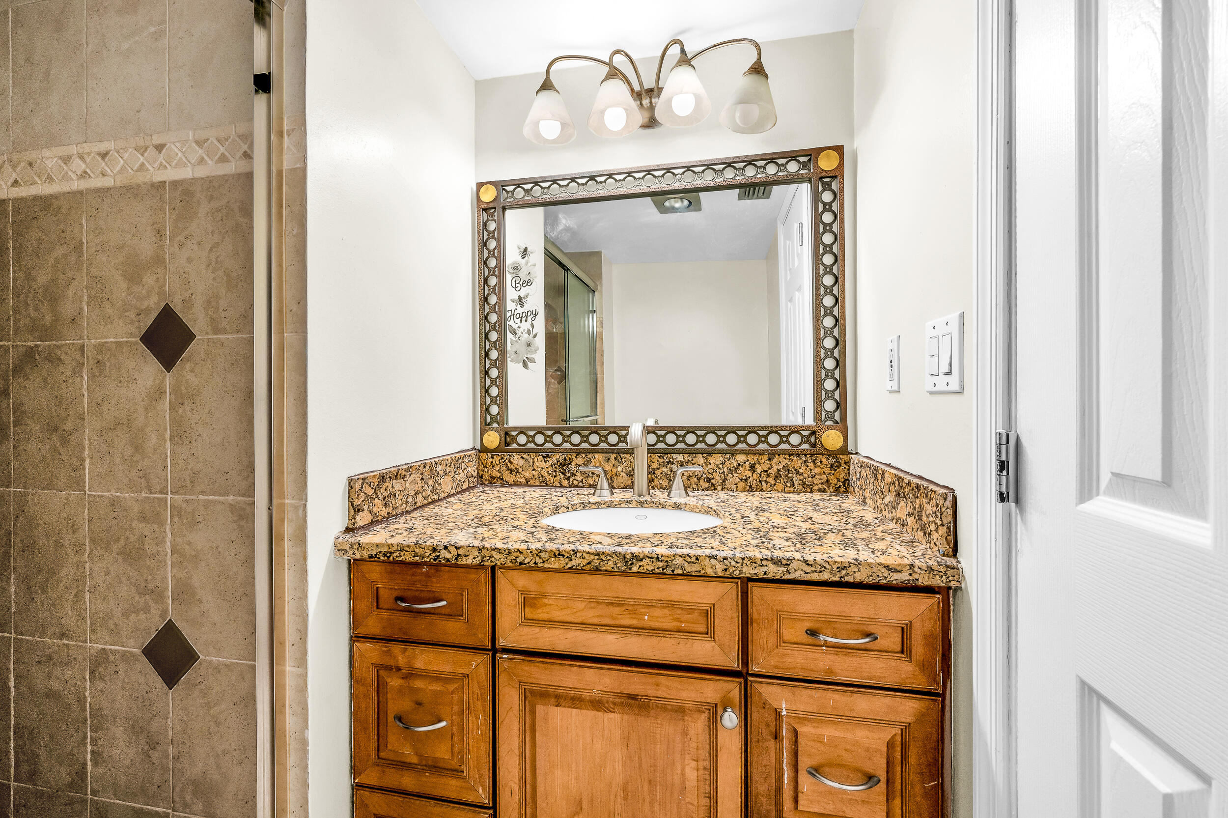 5340 Northwest 2nd Avenue, Unit 323 Boca Raton, FL 33487 - Photo 16 of 21 a bathroom with a granite countertop sink a mirror and a shower