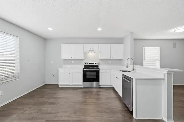 a large kitchen with a stove top oven and white cabinets