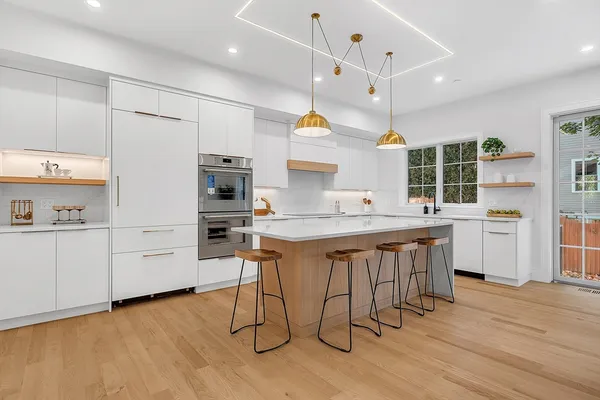 a kitchen with stainless steel appliances a stove a sink dishwasher and a refrigerator with wooden floor