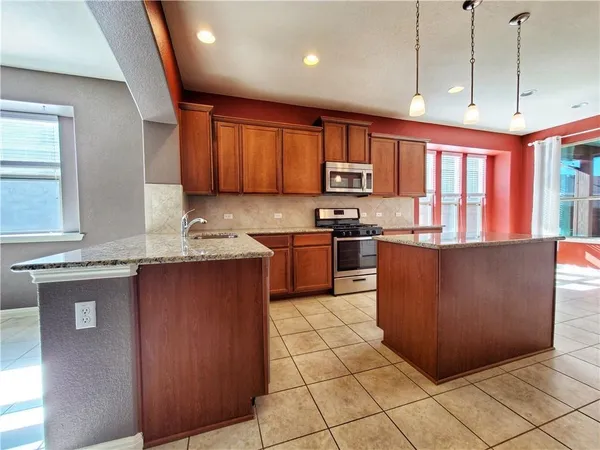 a kitchen with stainless steel appliances granite countertop a stove a sink and a microwave