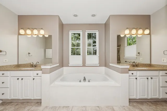 a bathroom with a granite countertop tub a double vanity sink and a large mirror