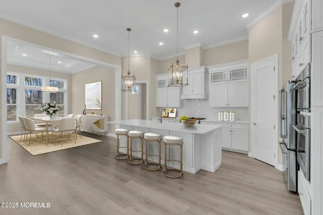 a kitchen with stainless steel appliances granite countertop a refrigerator a sink dishwasher a stove and white cabinets with wooden floor