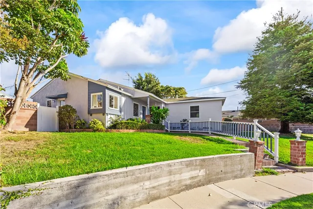 a front view of a house with a garden and a tree