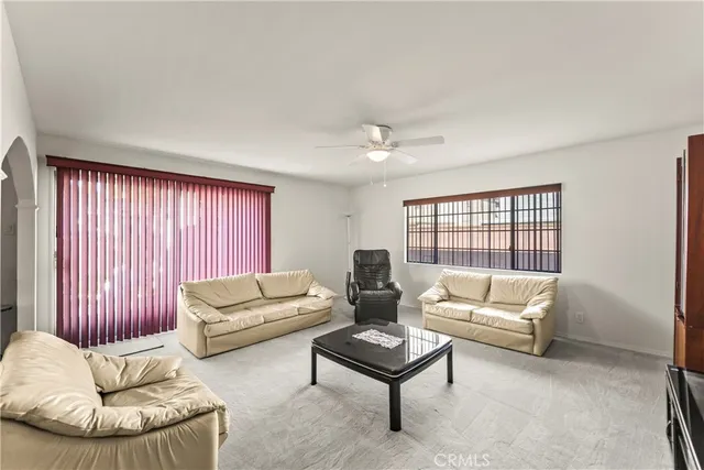 a living room with furniture a ceiling fan and a window