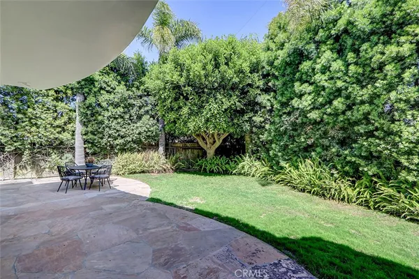 a patio with table and chairs and potted plants